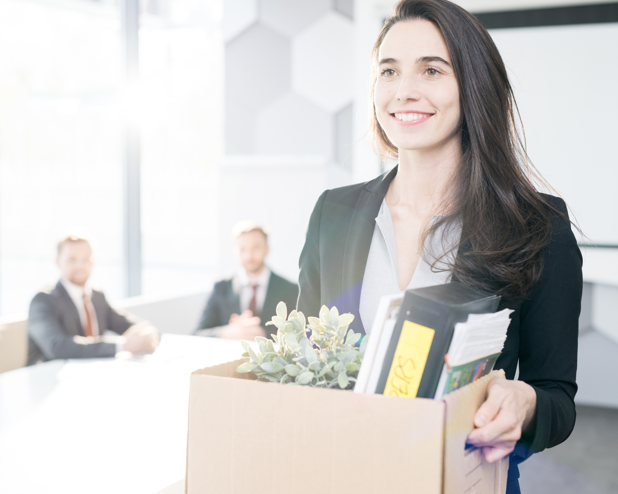 Woman holding a box with office supplies walking away from a meeting and smiling- How to Quit Your Job and Start a Sleep Consulting Business