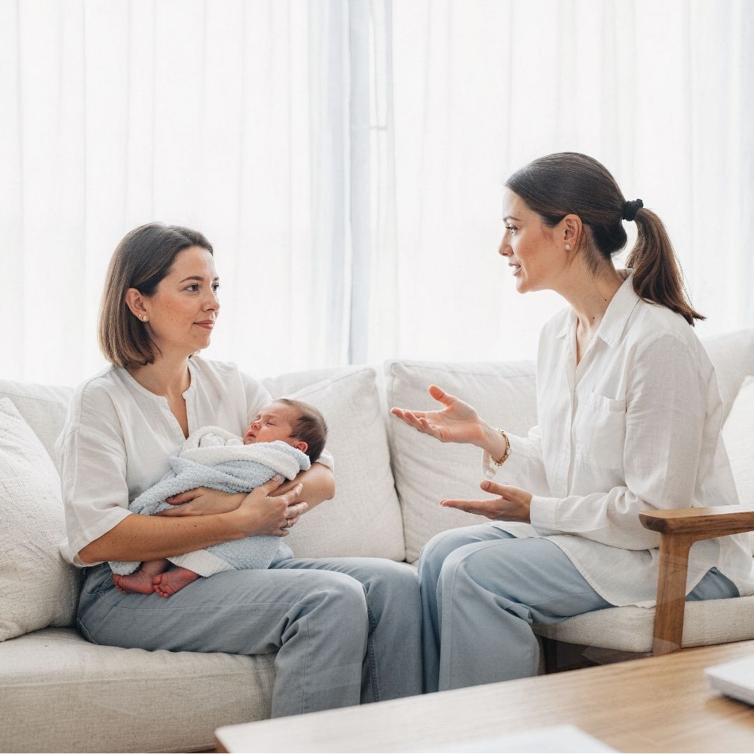 Sleep consultant sitting with mother and baby on couch